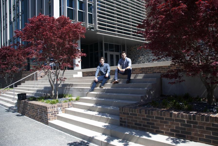 Two faculty sitting on the steps to the Trent Semans Center