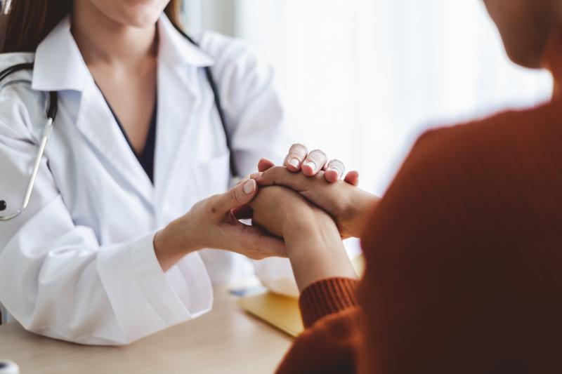 Healthcare provider holding the hands of a patient across a table