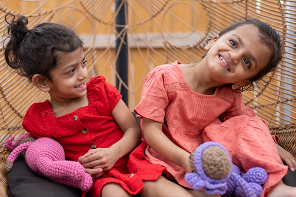 Twin girls sitting together in a wicker chair