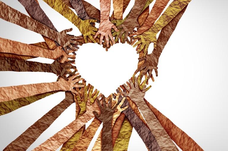 paper cutouts of hands and arms in different shades of skin tones reaching into a circle to make a heart shape