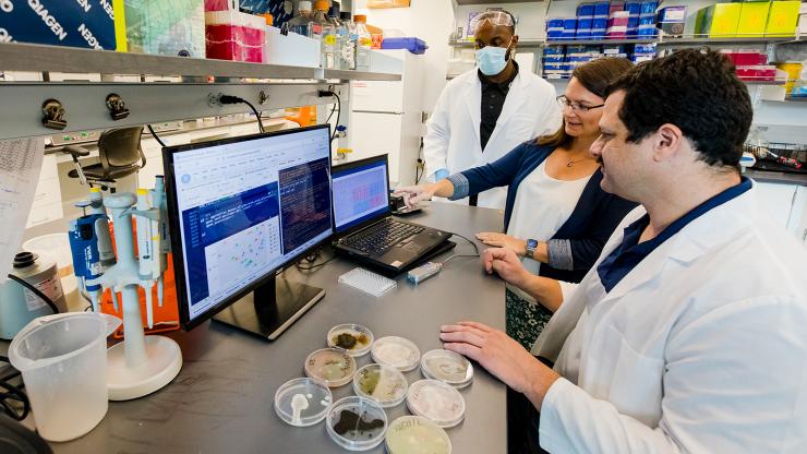 three people working in a lab and looking at a computer