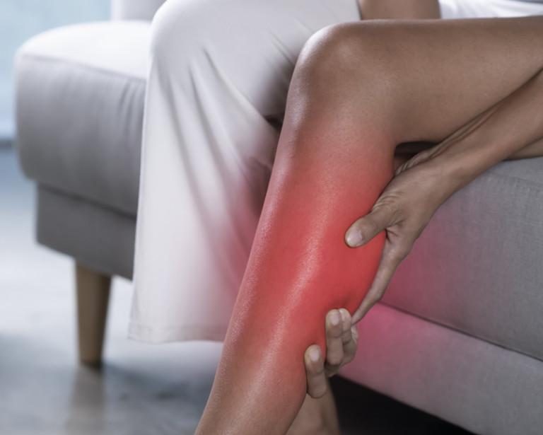 2 hands clutching their calf which is bright red to indicate pain. 