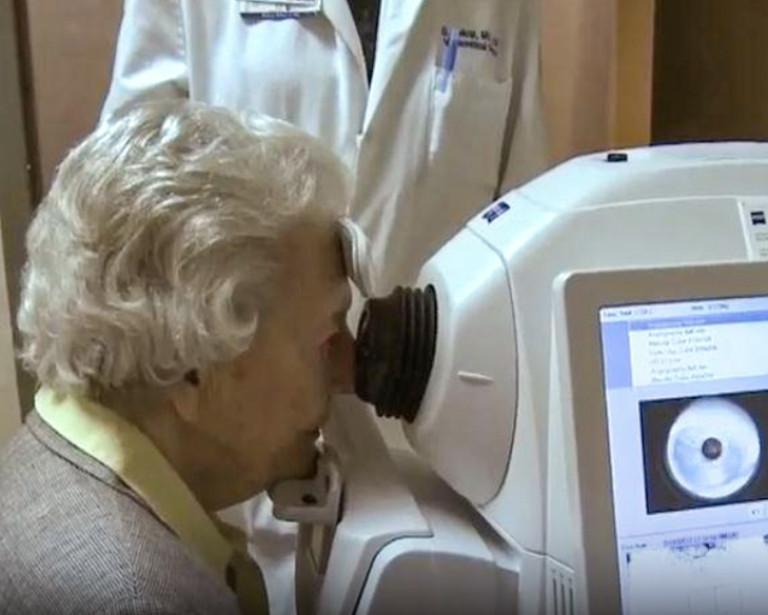 Elderly woman looking into an eye exam machine