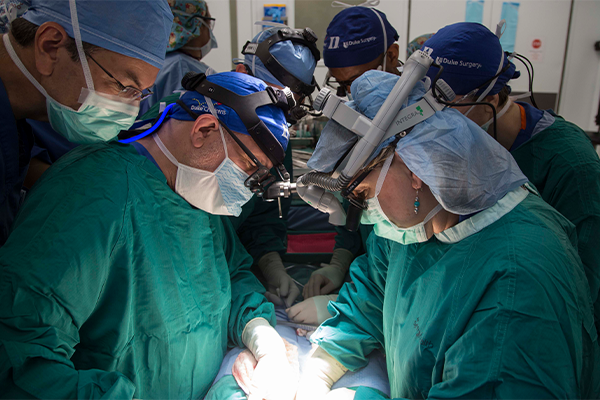 Dr. Sudan in an operating room performing surgery with other surgeons watching