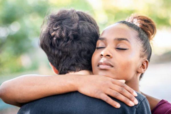 A woman hugging another person outdoors