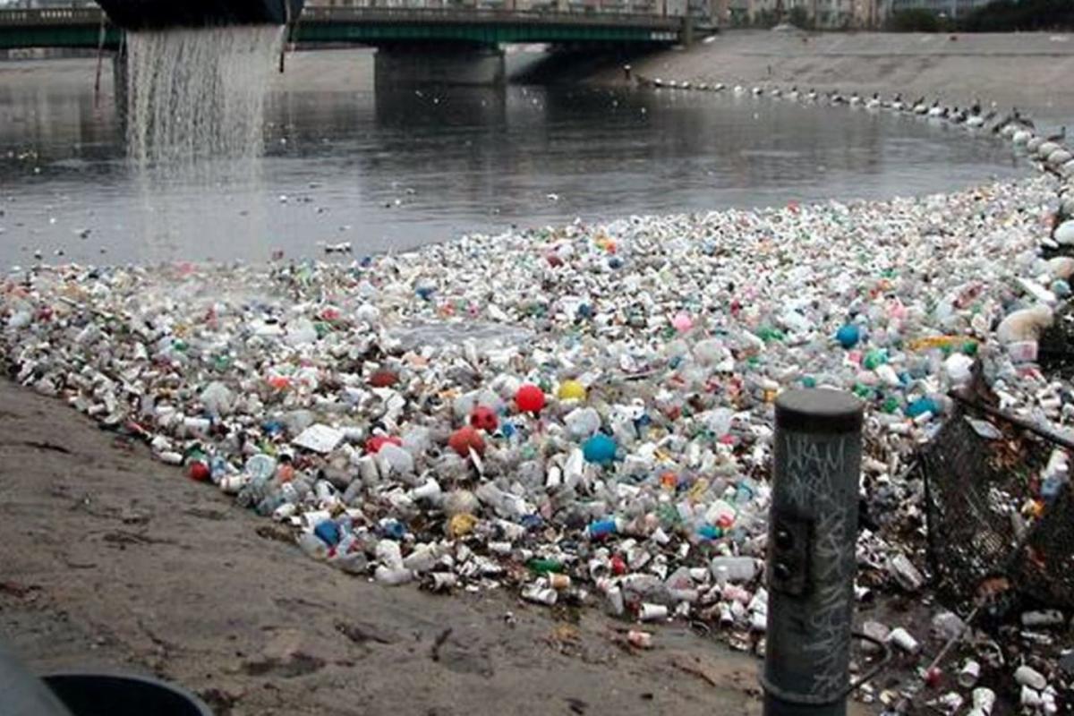 Plastic trash piles on the edge of a waterway.