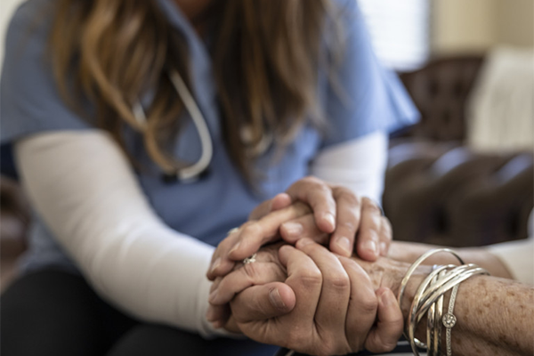 clasped hands of  a patient and healthcare worker