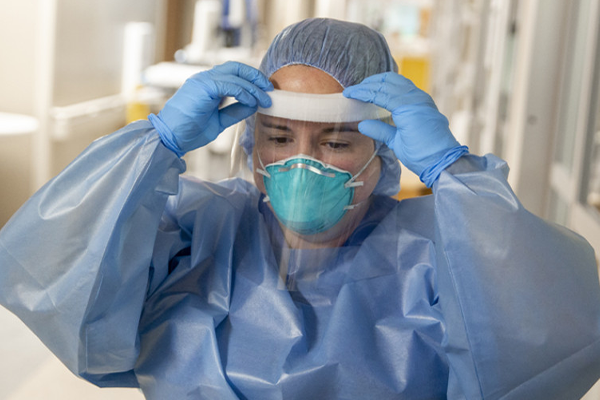 Healthcare provider donning PPE in a clinical setting