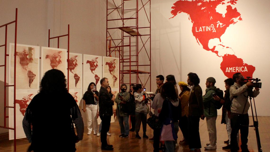 Crowd gathered around man speaking in art gallery