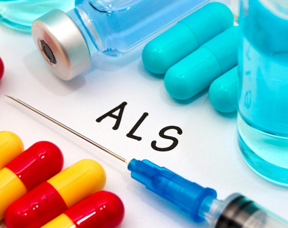 The letters ALS written on a piece of paper, surrounded by pills, a syringe and vials of medicine