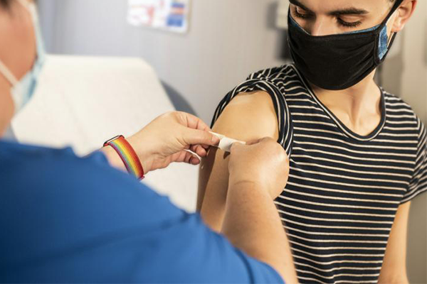 Young man receiving a having a bandage put on his upper arm.