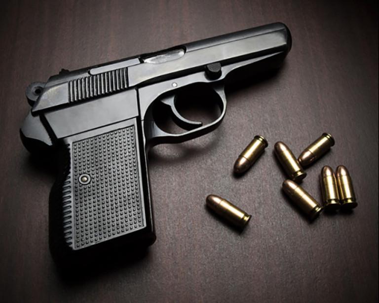 handgun and bullets laying on a table. 