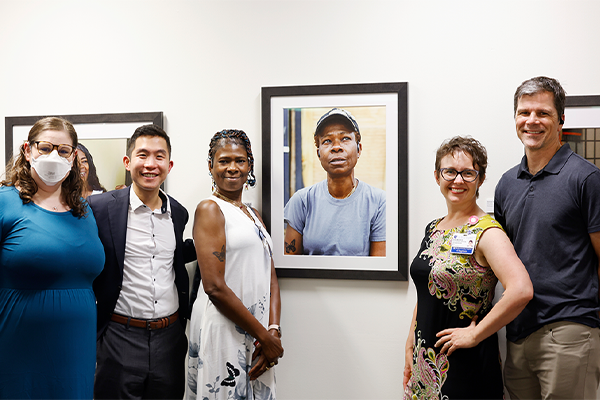 Butterfly Miles, center, poses near her portrait with the team during the opening of the Untold Stories Exhibition