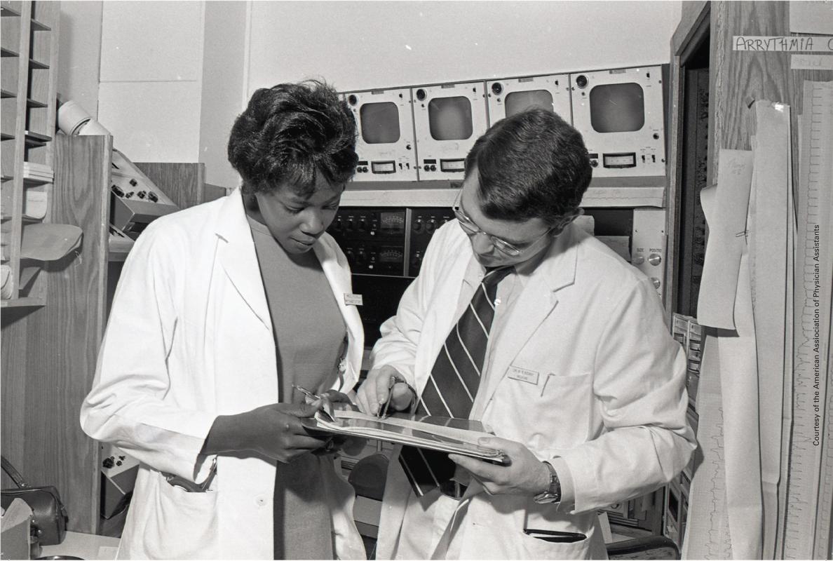 Archival image of Joyce Nichols examining a document with an unidentified physician
