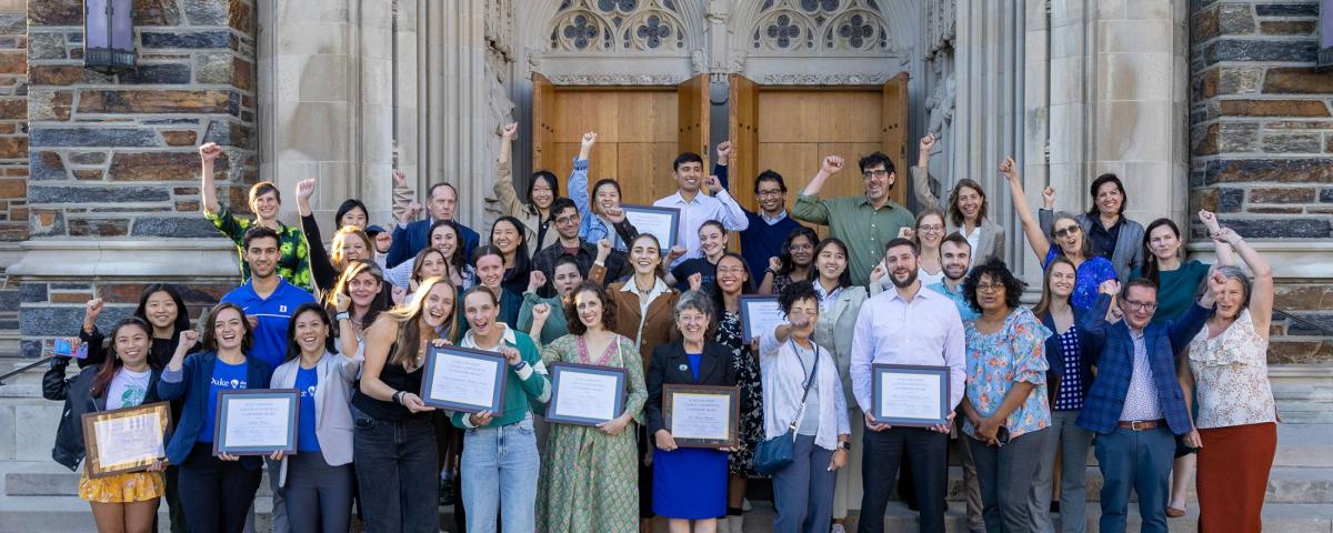 A group of people in front of a stone building cheering