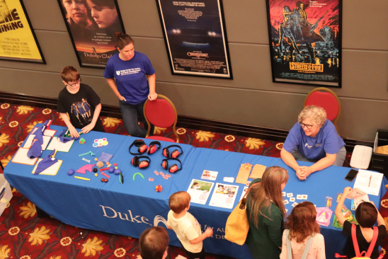 Duke faculty and staff greet children at a table with toys and other sensory-friendly items 