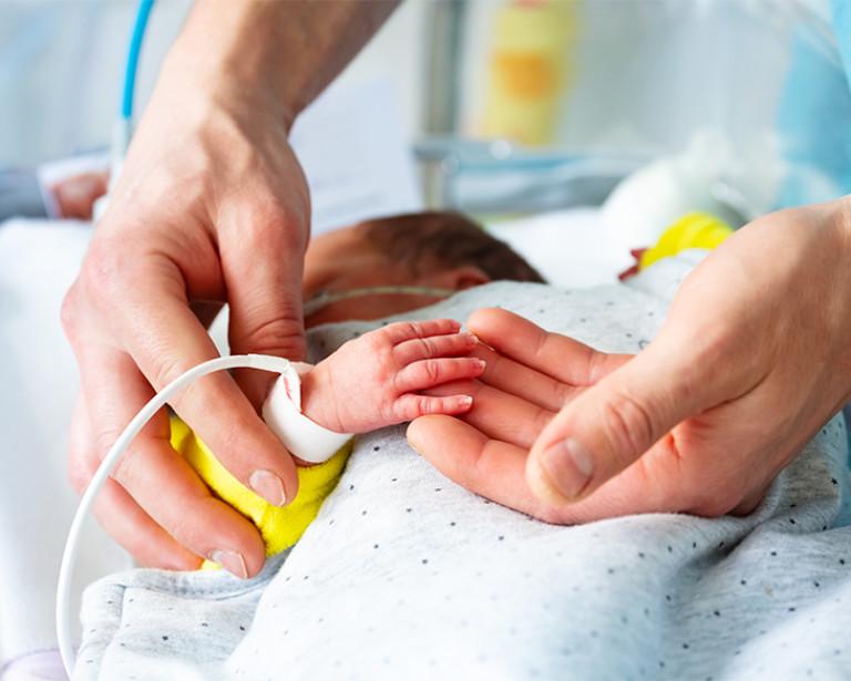 Closeup up adult's hands caring for an infant