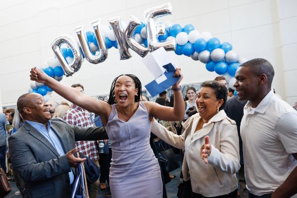 Excited student under Duke balloon banner