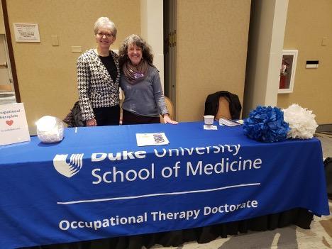 two women standing behind a Duke OTD booth