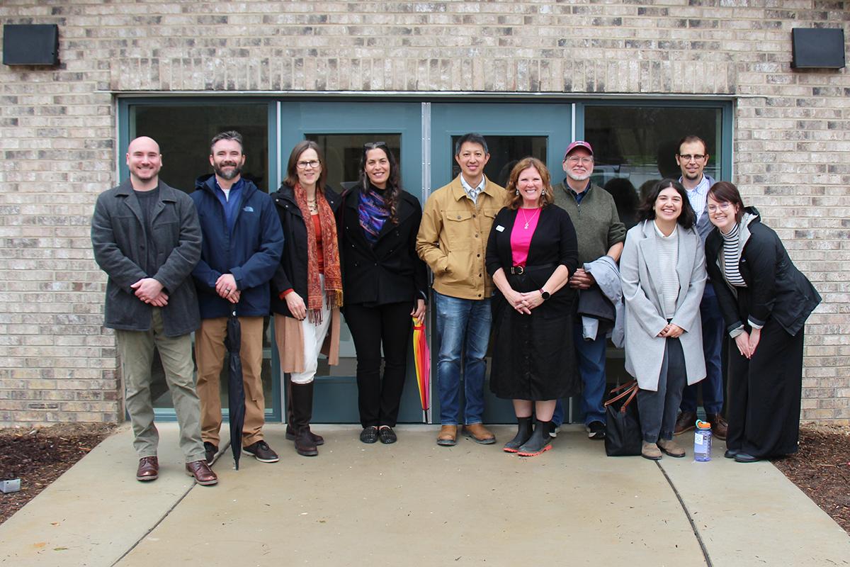 10 people standing in front of a building entrance posing for a photo