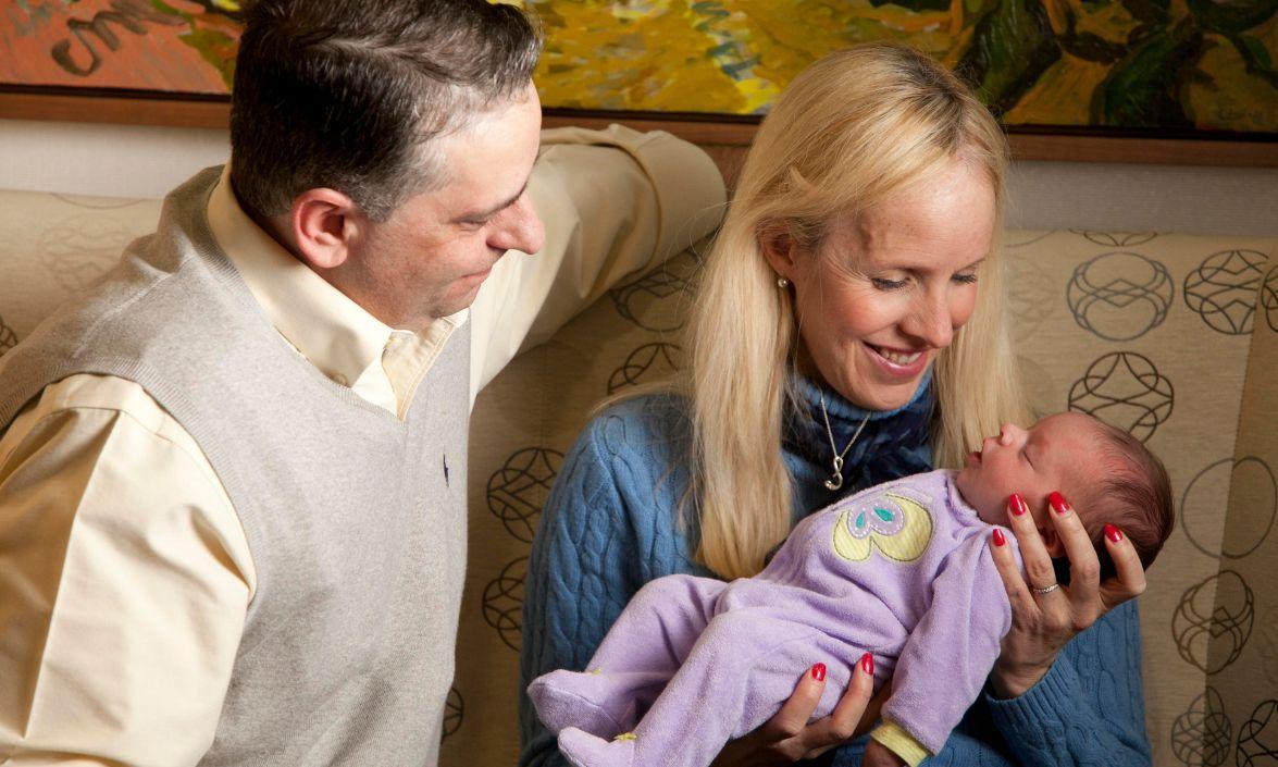 Sabrina Lewandowski holds her baby girl, Layla, while her husband, Greg, looks on