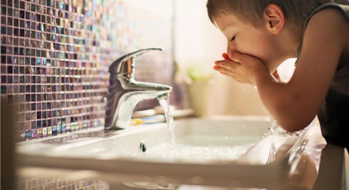 A child washing their face in running water