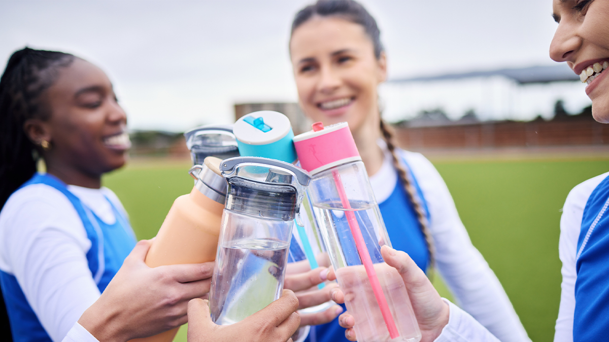 Three young teen girls toasting with their water bottles. 