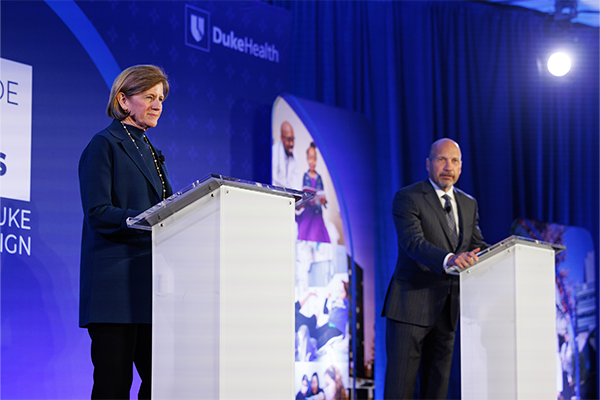 Mary Klotman, MD, and Craig Albanese, MD, MBA, standing behind podiums on stage. 