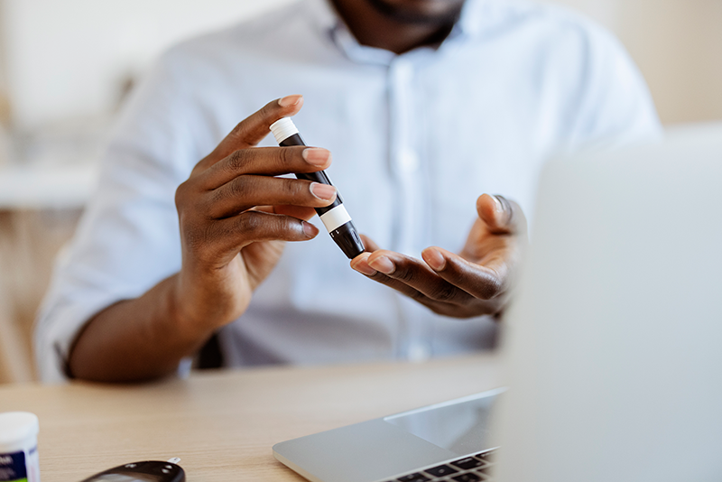 A man's hands using a tool to pierce his finger to check his blood sugar