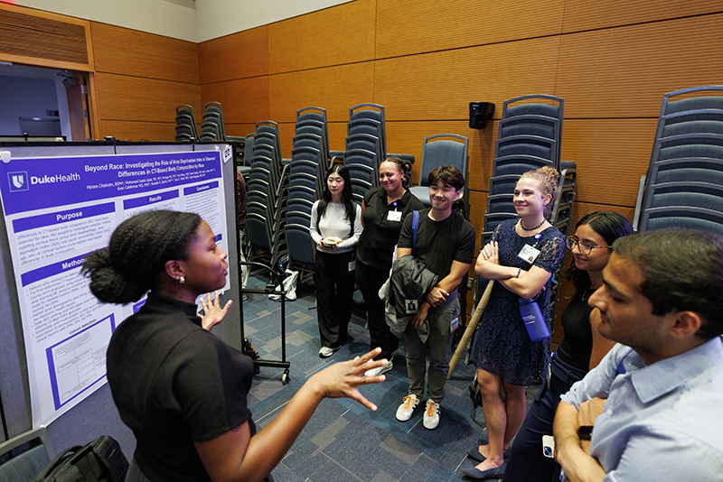 Miriam Chisholm, MS4, explains her research in front of her poster. 