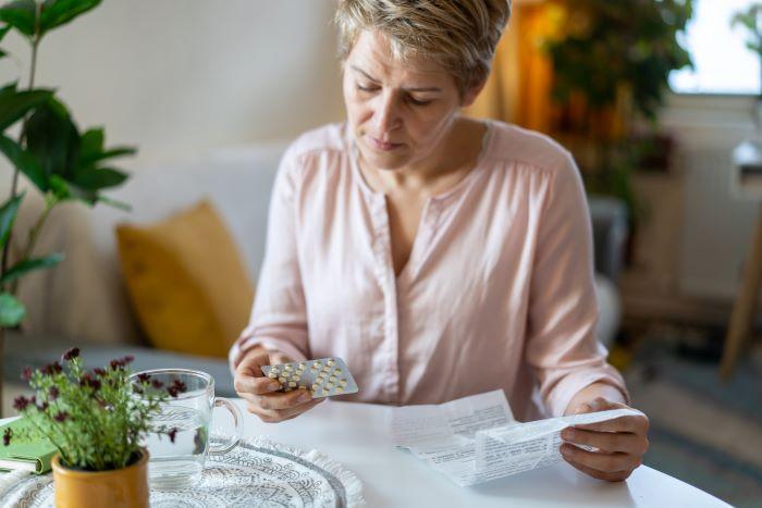Woman sitting at a table looking at many bottles of pills