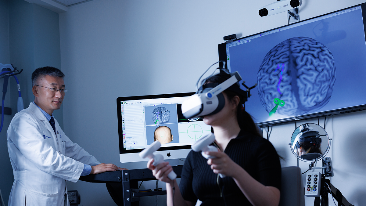 Dr. Wayne Feng works with a patient wearing a virtual reality headset at the Neurmodulation and Stroke Reovery Lab