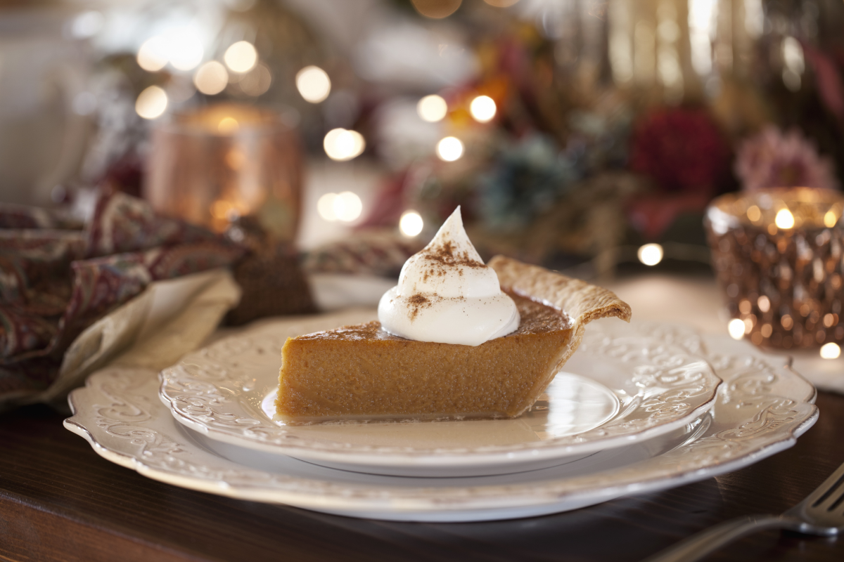 An attractively plated piece of pumpkin pie with whipped cream on top.