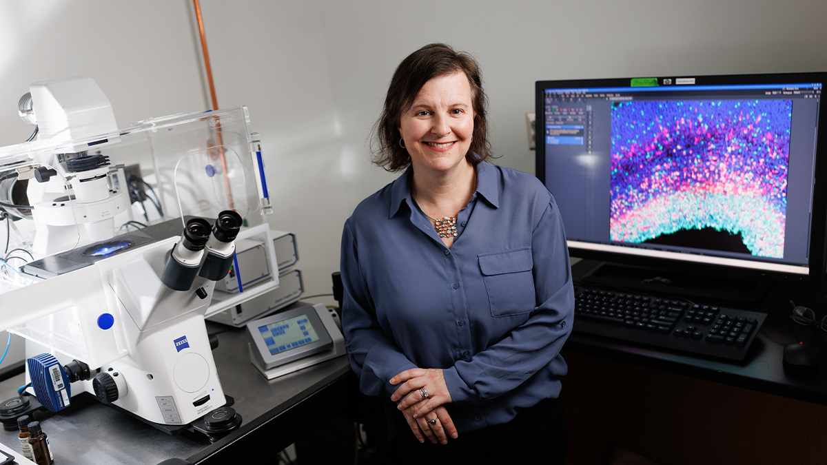 Debra Silver standing next to instruments in her lab