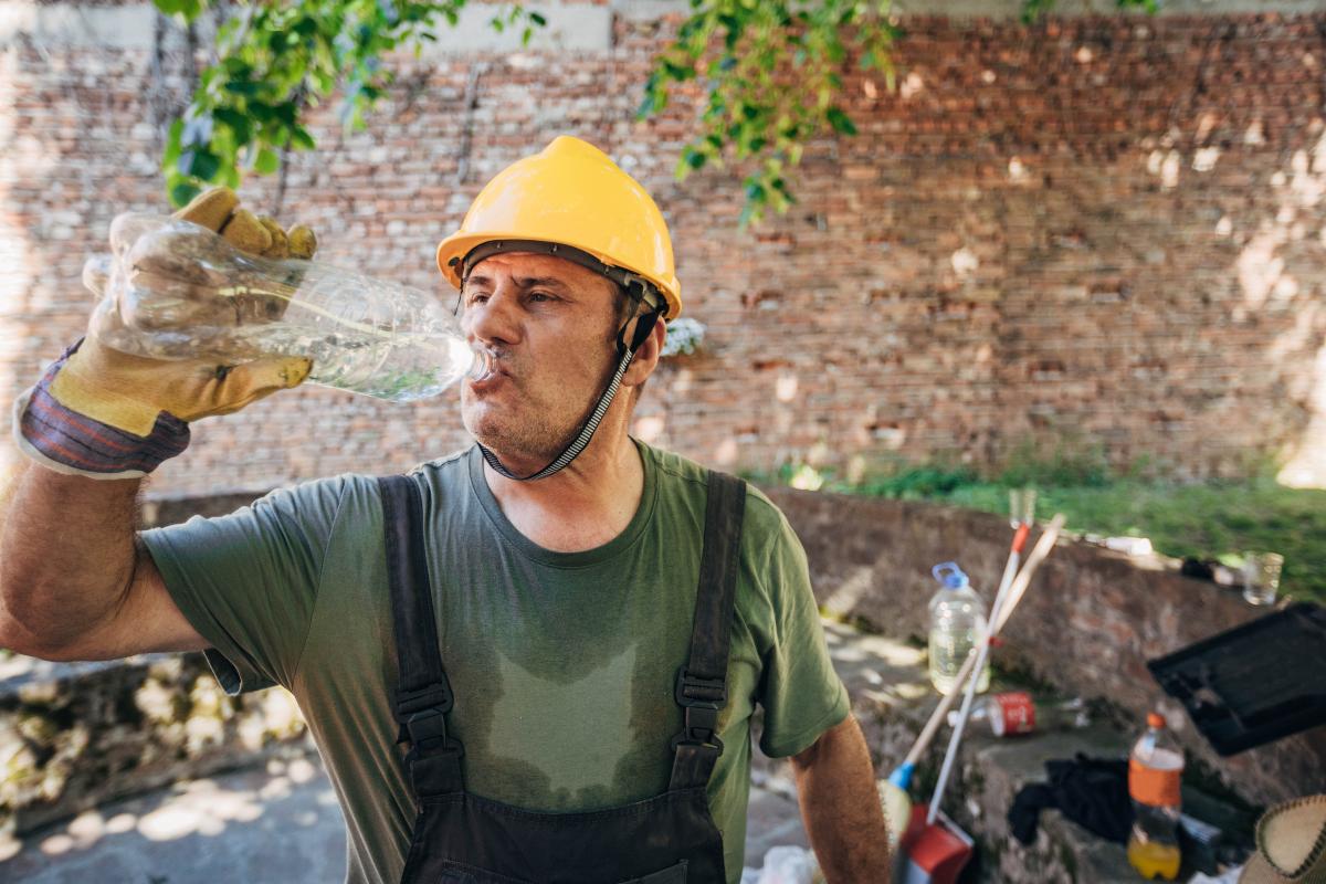 Stock image of a construction worker drinking a bottle of water on a hot day