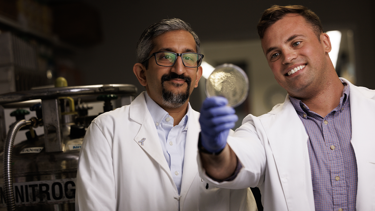 Sudarshan Rajagopal, MD, PhD and Preston Anderson examine a glass slide together.