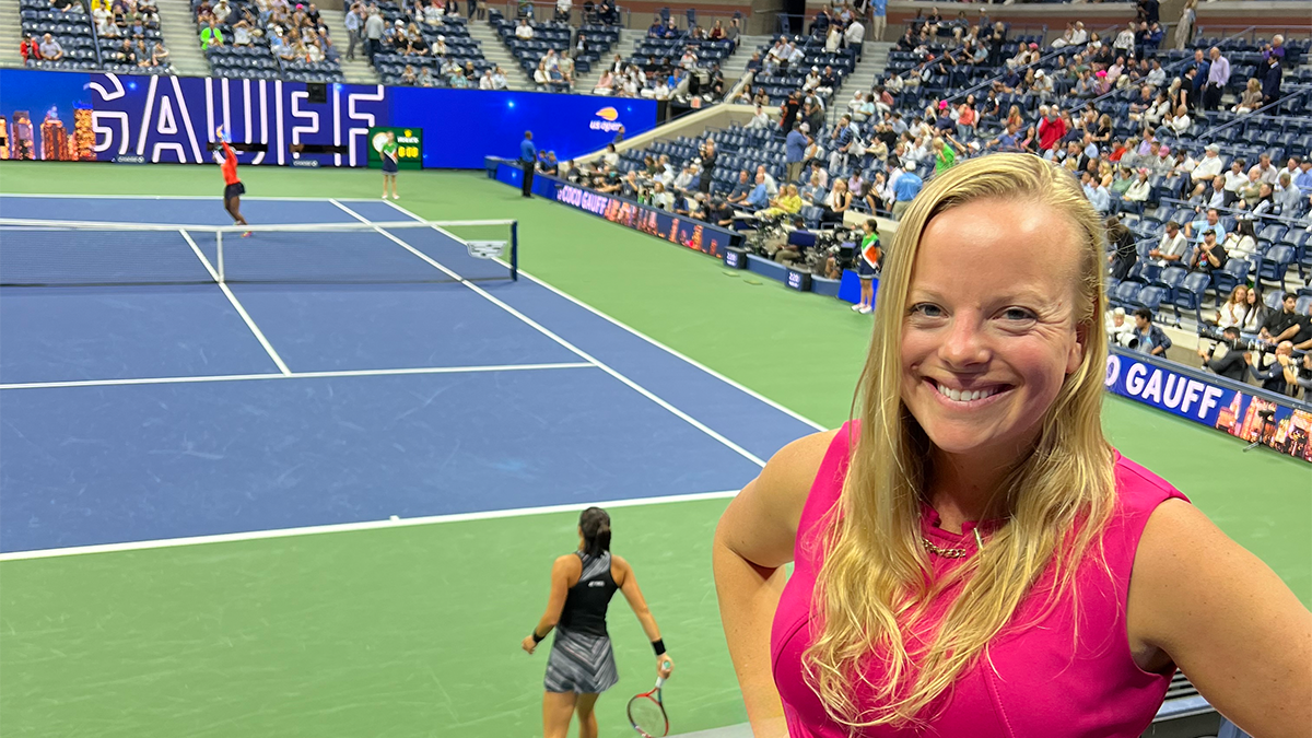 Laura yeager posing in front of a tennis court in play at the US Open