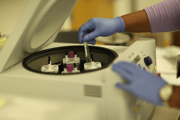 Image of health worker placing vials into a machine.