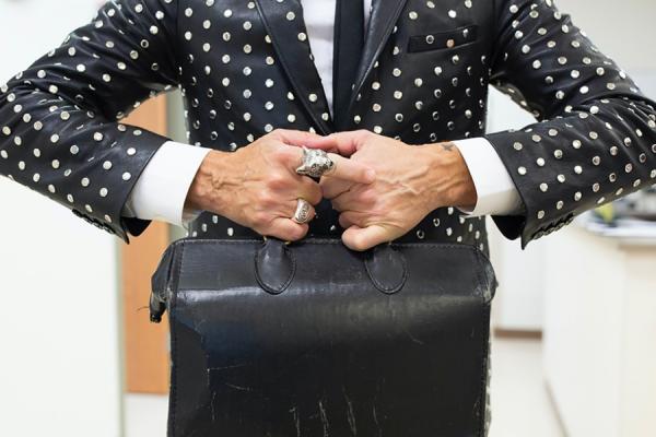 beringed physician's hands holding an old fashioned leather doctor's bag