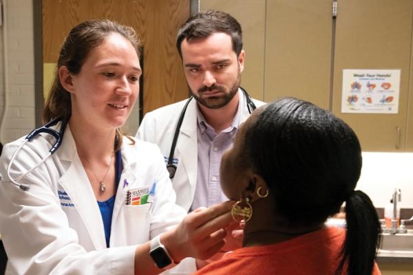 medical students examine a patient