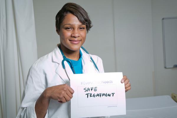 Dr. Kanecia Zimmerman holding a sign that say "Safe Treatment"