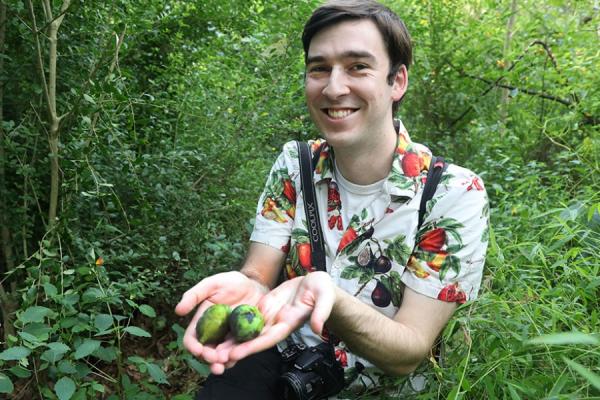 Jeff Letourneau in the woods holding 2 freshly picked paw paws