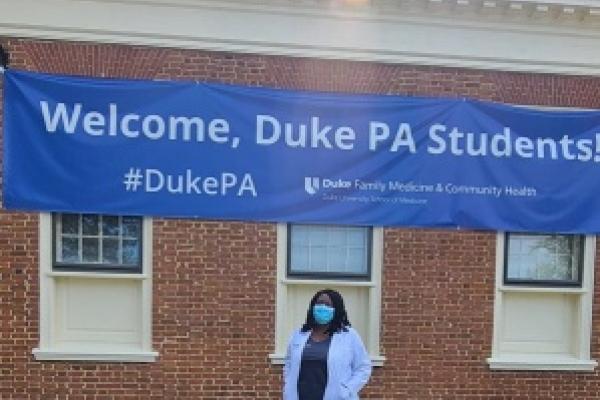 Second-year PA student Rayena McLaughlin poses in front of a welcome banner for the new class of PA students.