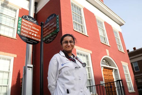 Rashmi Saincher, MBBS in her white coat standing outside brick building