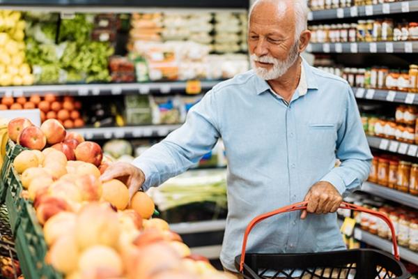 man with white beard and hair selecting produce at a grocery store