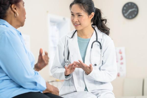 An Asian woman healthcare provider speaking with a Black woman patient.