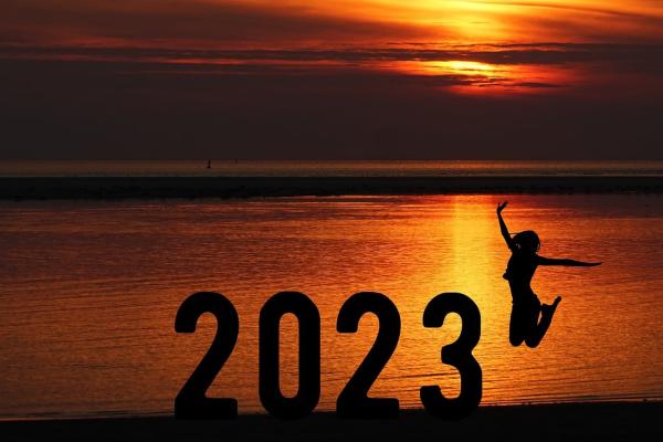 numbers 2023 on a beach at sunset with a person jumping next to them