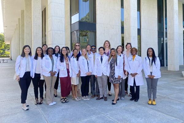 Duke PA students and faculty standing in front of building wearing their white coats