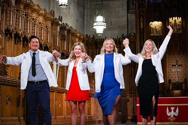 Four students with new white coats in Duke Chapel
