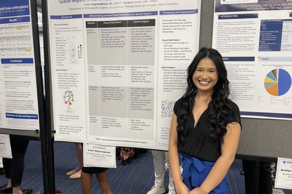 A student standing with her research poster
